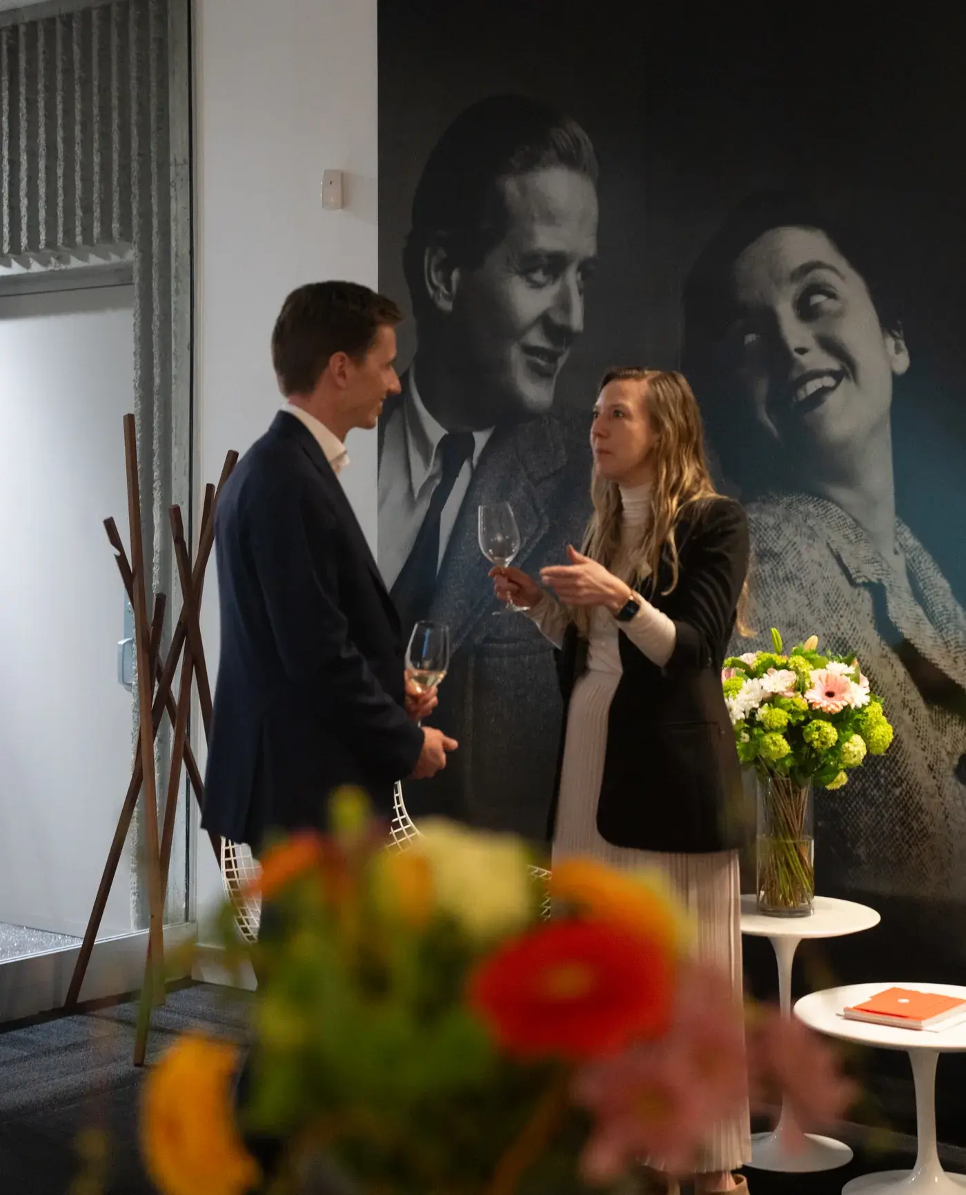 Two guests talking beside a large black-and-white design photograph